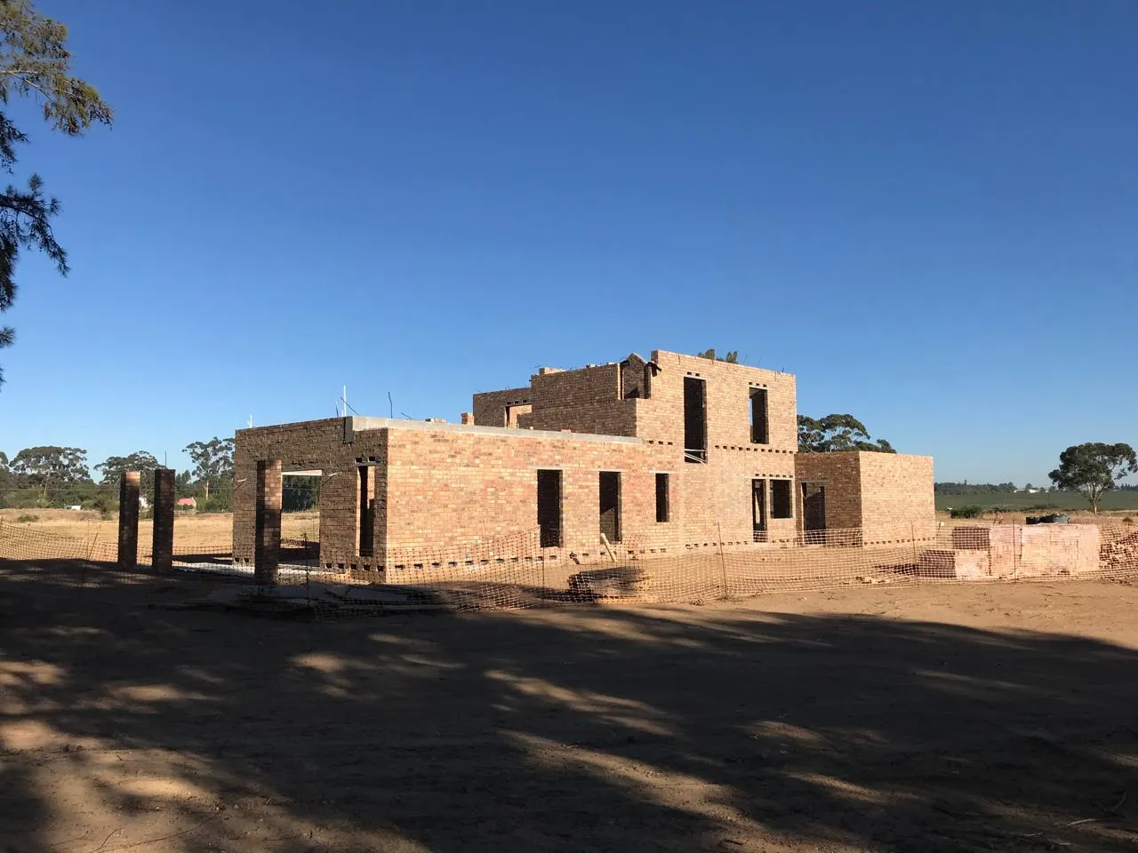 Face-brick walls rising on the Devonvale residence under a clear sky